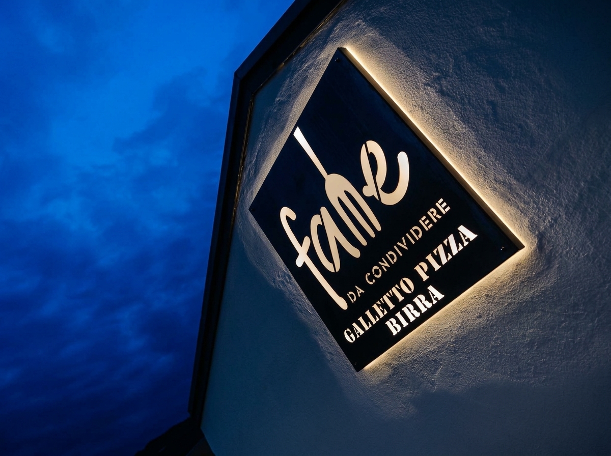 L'insegna illuminata di FAME sul cielo blu della sera